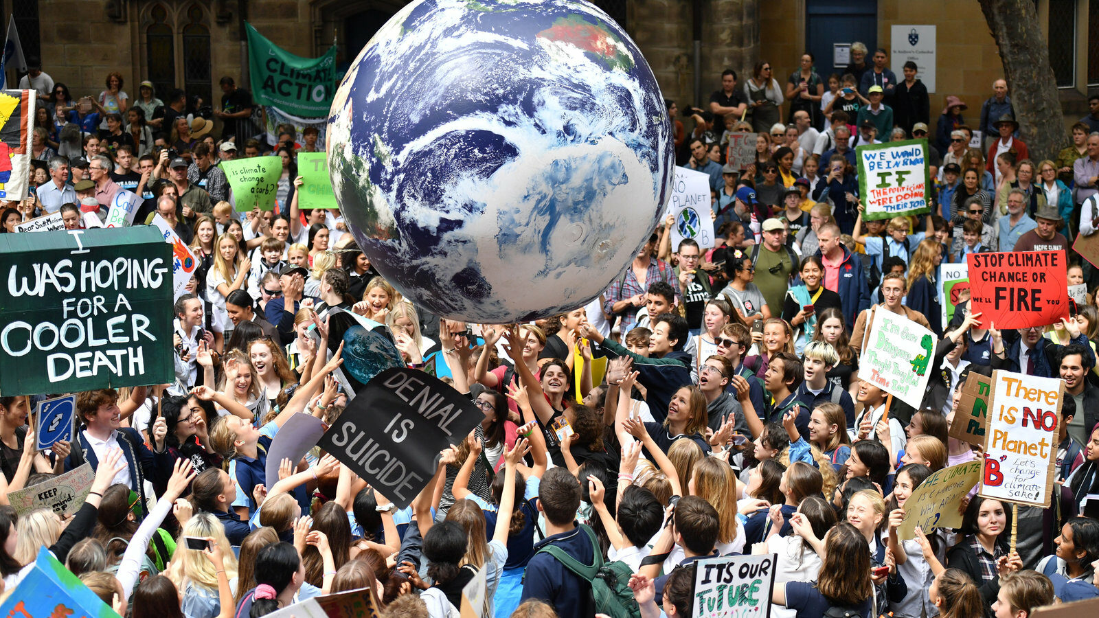 Youth Protestors holding up signs and a big balloon in the image of the earth.